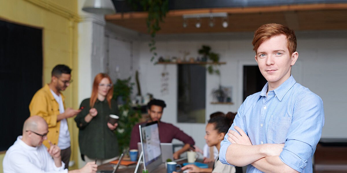 man-standing-beside-people-sitting-beside-table-with-laptops-3184395.jpg